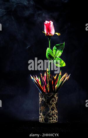 Questa foto creata utilizzando il fumo reale, una rosa rosa, e alcuni colorati pastelli a matita che danno all'immagine un aspetto mistico, ideale per un poster Foto Stock