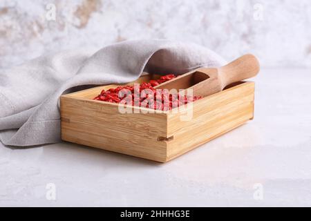 Scatola e paletta con frutti di bosco secchi su sfondo chiaro Foto Stock