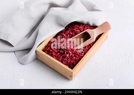 Scatola e paletta con frutti di bosco secchi su sfondo chiaro Foto Stock