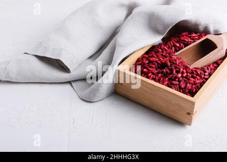 Scatola e paletta con frutti di bosco secchi su sfondo chiaro Foto Stock