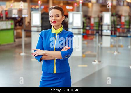 Donna allegra stewardess in piedi nel terminal dell'aeroporto Foto Stock