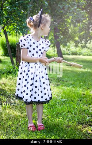 Bambina che cammina nel parco estivo con una piccola farfalla seduta sulla sua mano Foto Stock