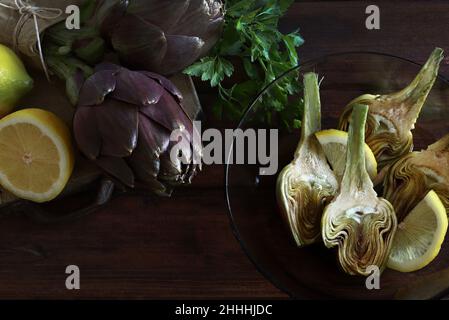 Carciofi freschi e biologici su sfondo di legno scuro. Direttamente sopra. Foto Stock