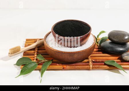 Ciotole con polvere di dente di carbone attivo e sale marino su sfondo bianco Foto Stock