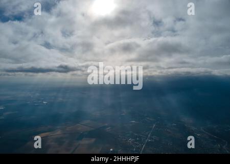 Vista aerea dalla finestra dell'aeroplano ad alta quota della città lontana coperta con strato di smog sottile e nubi distanti in serata. Foto Stock