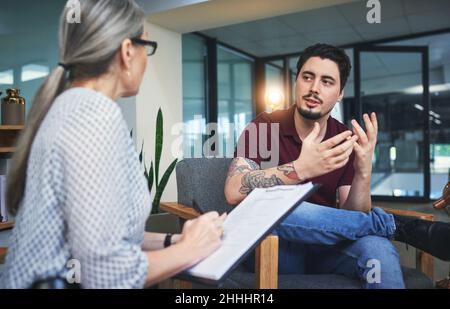 Dare una voce ai vostri sentimenti. Scatto di un giovane che ha una sessione terapeutica con uno psicologo. Foto Stock