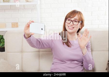 Sorridente donna di mezza età che prende selfie a casa. Spazio di copia Foto Stock