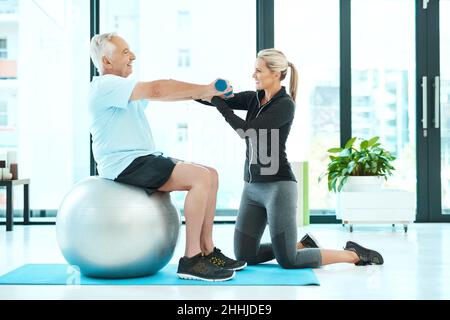 Lavorando su tutti quei muscoli rigidi. Shot di un fisioterapista che aiuta il suo paziente anziano con i suoi esercizi in un centro fitness. Foto Stock