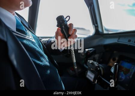 Pilota maschio che utilizza il microfono radio dell'aereo in cabina di pilotaggio Foto Stock