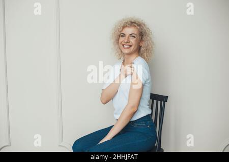 Donna che viene vaccinata contro il covid-19, mostrando braccio con bendaggio adesivo mentre si siede sulla sedia. Immunizzazione del virus corona. Donna che ottiene Foto Stock