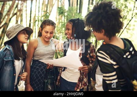 La vita è buona all'aria aperta. Foto di un gruppo di adolescenti che guardano una mappa mentre esplorano la natura insieme al campo estivo. Foto Stock