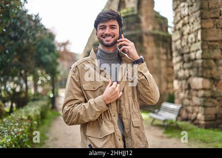 Vista laterale di gioiosa femmina in cuffie divertirsi con cane purebred in poltrona contro finestra in casa Foto Stock