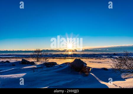 alba sopra la spiaggia ghiacciata vicino alle rocce Foto Stock