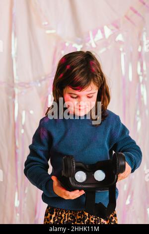 Ragazza premedetta positiva in piedi con moderni occhiali VR in studio con luce al neon Foto Stock