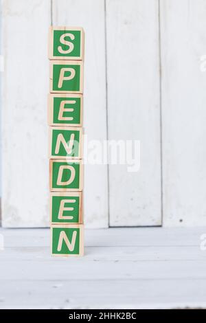 cubo di legno, con la parola spenden, su sfondo bianco Foto Stock