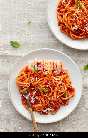 Vista dall'alto sulla deliziosa pasta fatta in casa con salsa bolognese servita con foglie di basilico fresco su piastra bianca Foto Stock