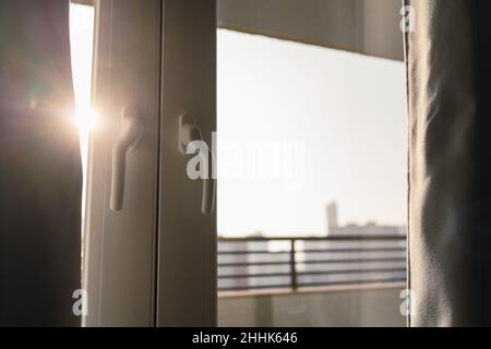 La luce del sole splende attraverso porte chiuse di balcone con tende oscuranti in un moderno appartamento in un edificio residenziale a più piani Foto Stock