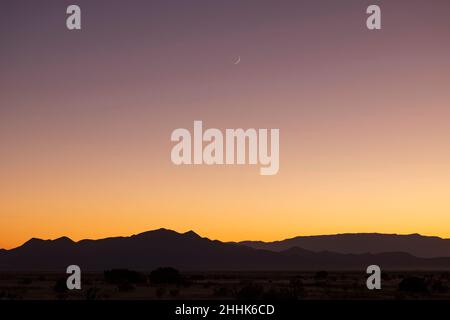 USA, New Mexico, Santa Fe, Crescent moon sopra le montagne di Jemez al tramonto Foto Stock