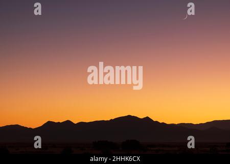 USA, New Mexico, Santa Fe, Crescent moon sopra le montagne di Jemez al tramonto Foto Stock