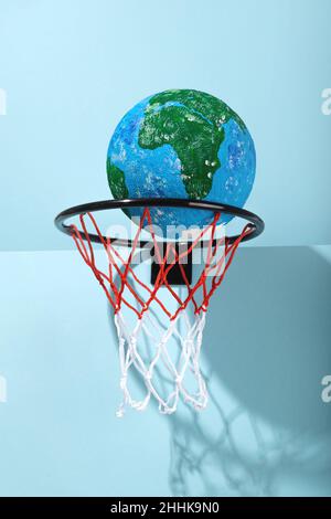 Pianeta rotondo Terra con acqua e terra in basket con rete colorata su sfondo chiaro con luce solare e ombra Foto Stock