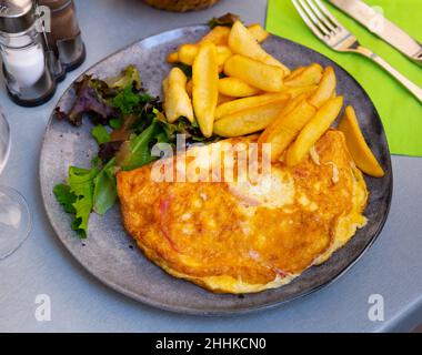 Porzione di omelette gourmet con patate fritte Foto Stock