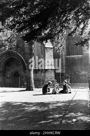 Confidenze infantili nel parco giochi della scuola ragazze accanto alle mura dell'abbazia di Tewesbury in Gloucestershire.June 1935 Foto Stock