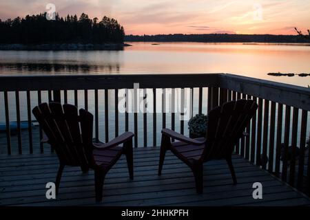Guardando il tramonto dalle sedie a sdraio che si affacciano sul fiume Foto Stock