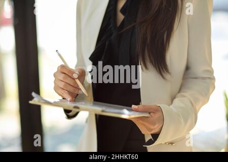 Crosed colpo, Businesswoman in piedi in ufficio e tenendo un libro cartaceo finanziario della clipboard. Foto Stock