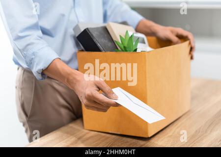 Concetto di dimissioni l'ufficiale maschio in piedi, mettendo la sua scatola di suo appartiene sulla scrivania e consegnando la lettera bianca a qualcuno. Foto Stock