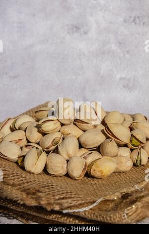 Pistacchi in sacco di burlap su tavola di cemento. Pistacchi organici. Vegan cibo sano ad alta proteina. Alimentazione dietetica. Concetto di NUTS Foto Stock