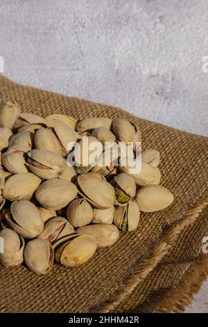 Pistacchi in sacco di burlap su tavola di cemento. Pistacchi organici. Vegan cibo sano ad alta proteina. Alimentazione dietetica. Concetto di NUTS Foto Stock