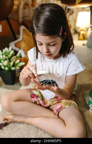 Ragazza che gioca osservando bug giocattolo con una lente di ingrandimento Foto Stock