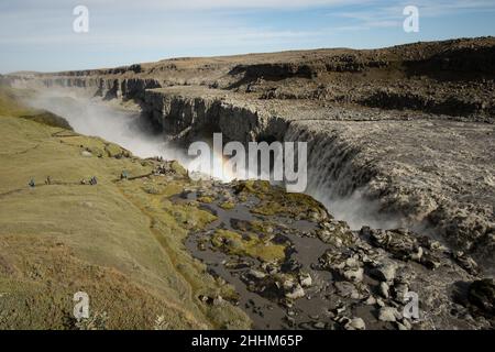 Arcobaleno e acqua grigio scuro di brutale cascata in Islanda Foto Stock