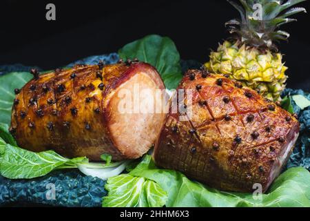 Giunto di gammon cotto con ananas intero su sfondo nero Foto Stock