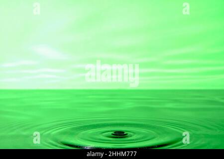 Sfondo verde brillante con cerchi divergenti da gocce d'acqua di superficie Foto Stock