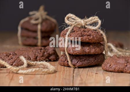 Biscotti Choc-chip impilati l'uno sull'altro legati con una stringa marrone (fuoco selettivo) Foto Stock