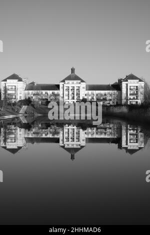 Vista di un edificio residenziale e il riflesso di esso su un lago in bianco e nero Foto Stock