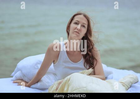 Ritratto di una bella giovane donna sulla spiaggia seduta sul letto. Foto Stock