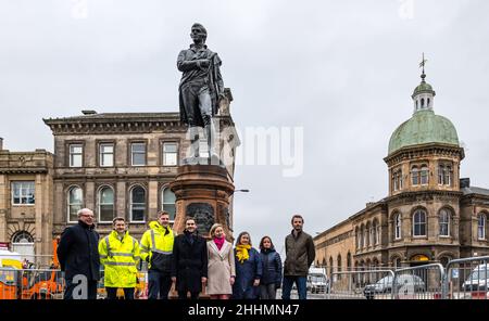 Leith, Edimburgo, Scozia, Regno Unito, 25 gennaio 2022. La statua di Robert Burns svelata: La statua, che è stata rimossa nel 2019 per i tram per i lavori di costruzione di Newhaven, ritorna a Bernard Street recentemente restaurato sulla notte Burns. La statua fu eretta dal Leith Burns Club nel 1898. Su ciascun lato del piedistallo si trova un pannello basato su una delle poesie del Bard. Nella foto: Il leader del consiglio comunale di Edimburgo Adam McVey e il consigliere Lesley Macinnes si uniscono ai membri del progetto di costruzione alla presentazione Foto Stock