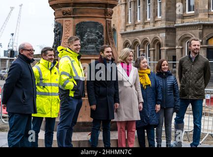 Leith, Edimburgo, Scozia, Regno Unito, 25 gennaio 2022. La statua di Robert Burns svelata: La statua, che è stata rimossa nel 2019 per i tram per i lavori di costruzione di Newhaven, ritorna a Bernard Street recentemente restaurato sulla notte Burns. La statua fu eretta dal Leith Burns Club nel 1898. Su ciascun lato del piedistallo si trova un pannello basato su una delle poesie del Bard. Nella foto: Il leader del consiglio comunale di Edimburgo Adam McVey e il consigliere Lesley Macinnes si uniscono ai membri del progetto di costruzione alla presentazione Foto Stock