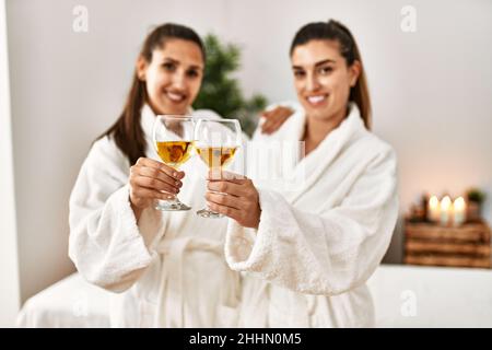 Due donne indossano accappatoio tostando con champagne in piedi al centro di bellezza Foto Stock