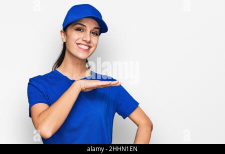 Giovane ispanica ragazza che indossa corriere uniforme gesturing con le mani che mostrano grande e grande segno di misura, simbolo di misurazione. Sorridente guardando il venuto Foto Stock