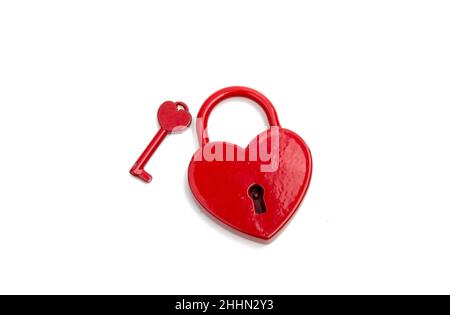 cuore rosso metalico con una chiave sul bianco Foto Stock