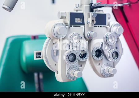 Strumento ottico per la misurazione della vista. Apparecchiatura per test oculari. Strumento di esame occhi bianchi con sedia oftalmologica verde Foto Stock