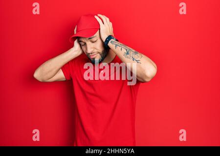 Uomo ispanico con barba che indossa uniforme di consegna e cappuccio che soffre di mal di testa disperata e stressata perché il dolore e l'emicrania. Mani sulla testa. Foto Stock