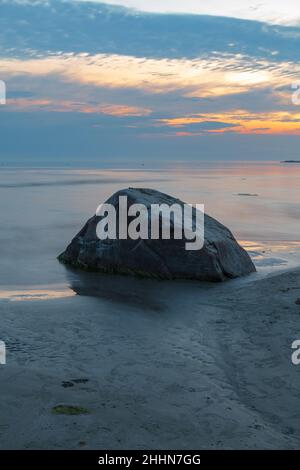 Ora blu dopo il tramonto sul mar Baltico roccioso costo. Piccole pietre e grandi massi in mare. Esposizione prolungata Foto Stock