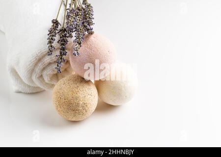 Bombe da bagno fatte in casa con fiori secchi di lavanda e asciugamano bianco. Cosmetici naturali Foto Stock