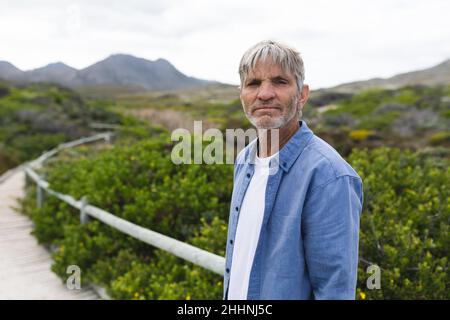 Ritratto di uomo maturo caucasico in piedi sul lungomare durante il fine settimana. Stile di vita, fine settimana e natura concetto. Foto Stock
