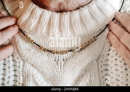 Tutte le età contano, l'età è solo un numero, la popolazione più anziana, i giovani a cuore, gli anziani. Le mani femminili anziane che tengono i branelli con il testo l'età è giusta a. Foto Stock