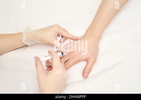 Iniezione di palma al centro benessere. Il medico ha le mani nei guanti. Primo piano. Abbastanza paziente Foto Stock